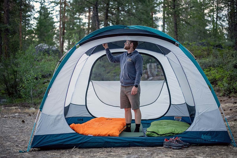 Người đàn ông đứng trong lều cắm trại màu trắng xanh