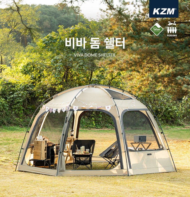 Lều cắm trại kazmi màu be được đặt trên nền cỏ xanh, bên trong có bàn ghế và đồ cắm trại cần thiết